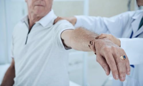 Pacjent z wyciągniętą ręką jest diagnozowany przez osteopatę w celu wykrycia źródła bólu.